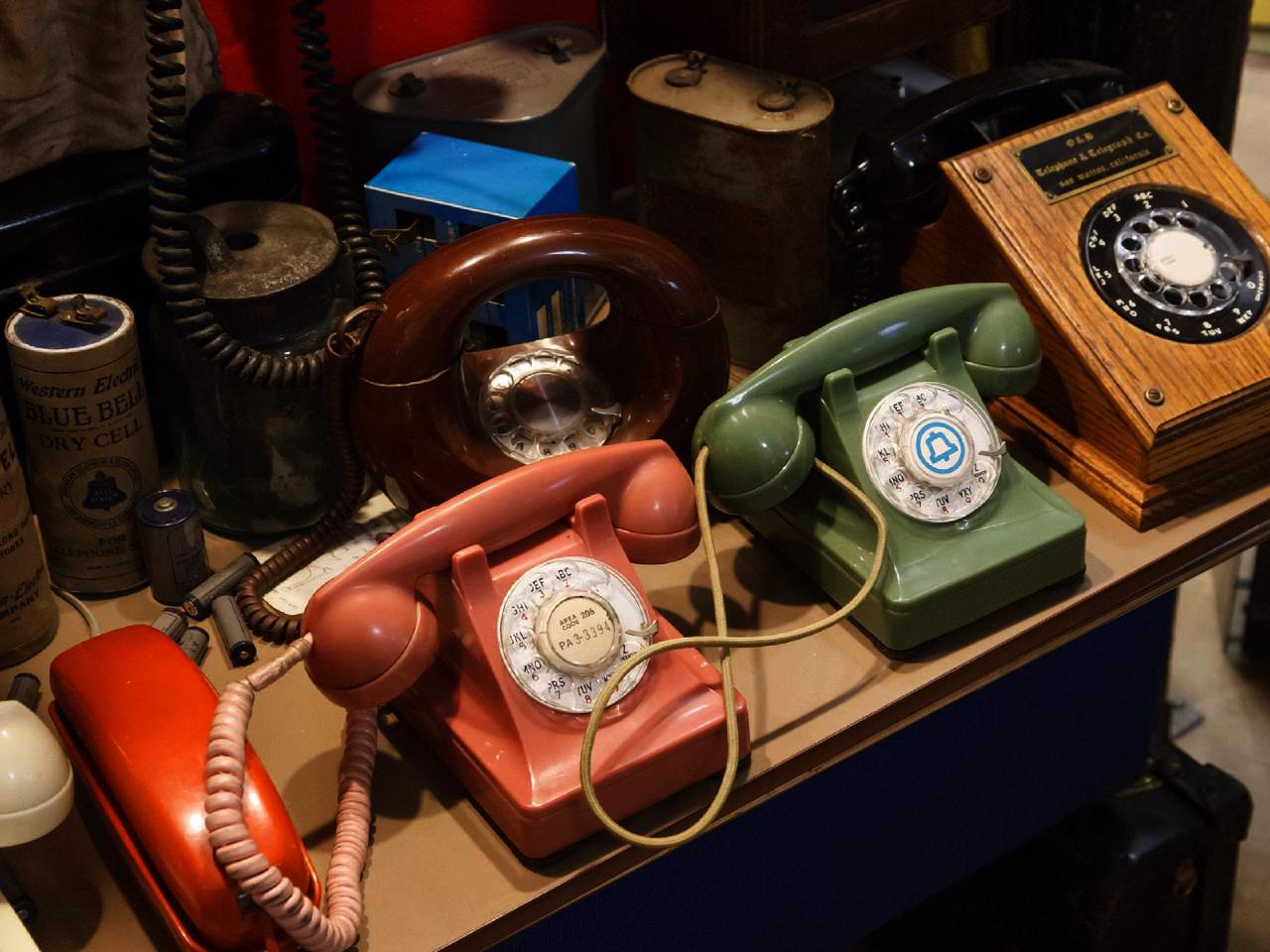 Vintage desk telephones in a line on a desk.