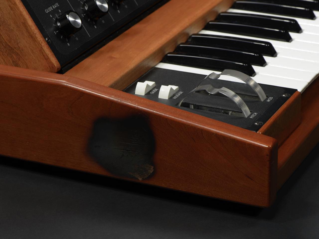 Close-up image of the control panel for a vintage analog synth, with rows of physical buttons, dials, and quarter-inch phono jacks.